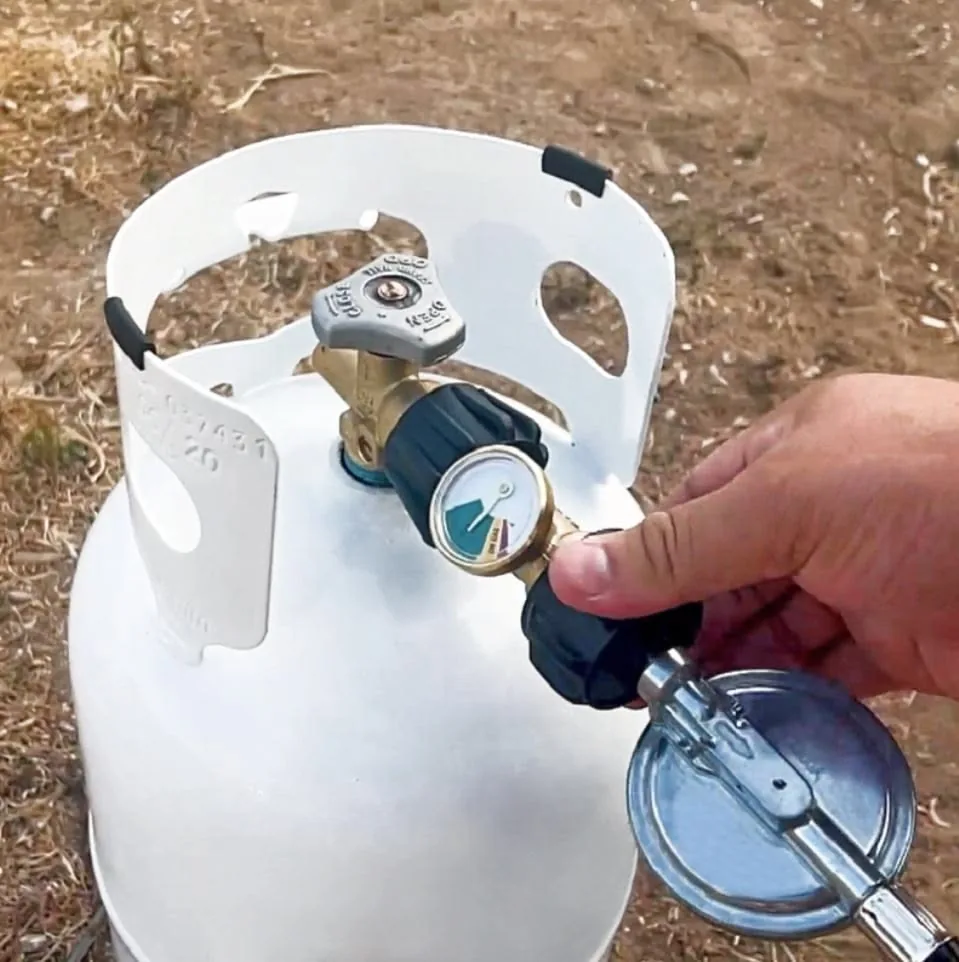 Hand checking the regulator gauge on a propane cylinder