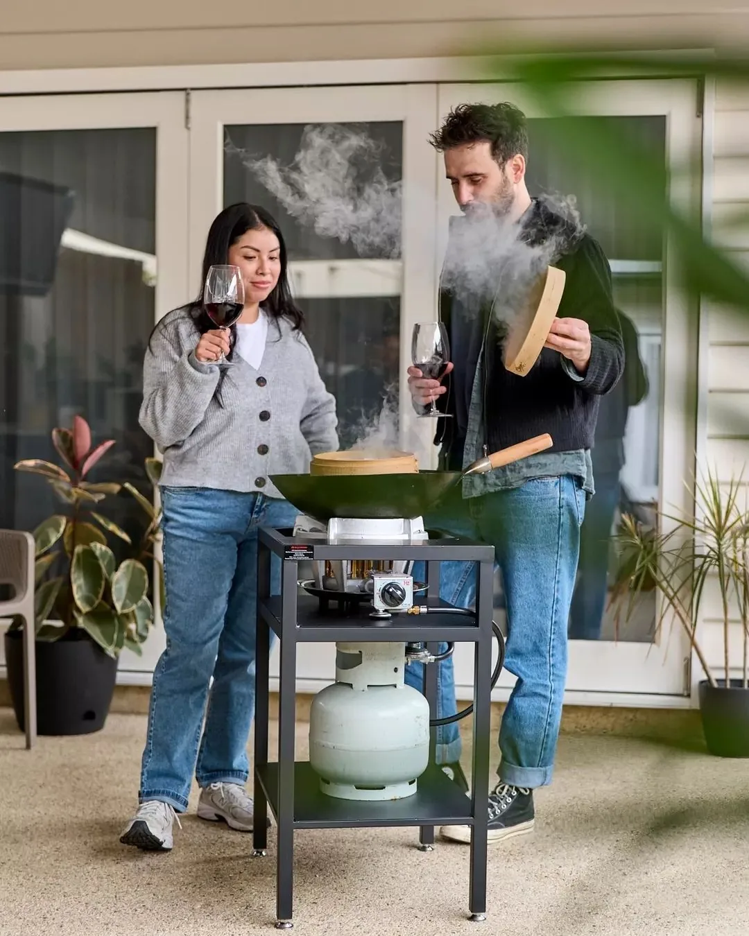 Couple cooking outdoors using a propane-powered cooking setup